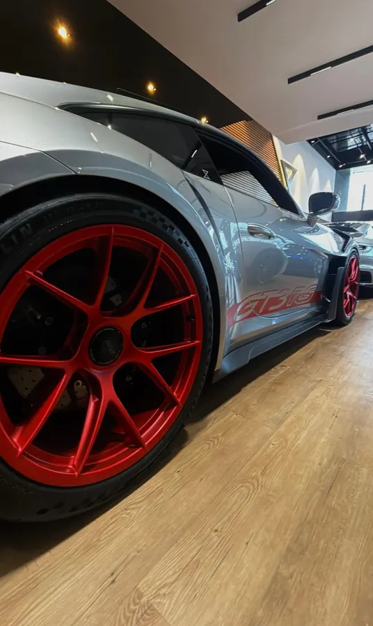 Porsche 911 GT3 RS cinza com rodas vermelhas em showroom